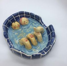 there are three small figurines floating in a blue bowl with white tiles on it