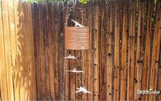 a bird feeder hanging from the side of a wooden fence next to a tall pole