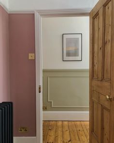 an empty room with pink walls and wood flooring is seen through the door to another room