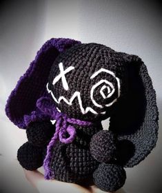 a crocheted black and purple stuffed animal with an x on it's face