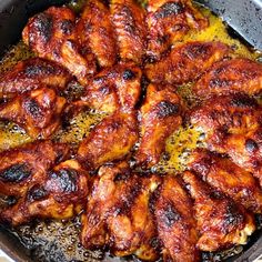 chicken wings cooking in a skillet with oil on the top and yellow sauce on the bottom