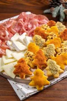 cheeses and meats are arranged on a platter with pine cones in the background