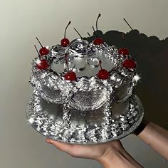 a person holding a cake with cherries on it