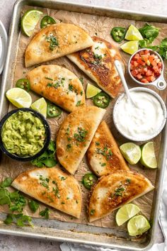 quesadillas with guacamole, salsa and sour cream on a baking sheet