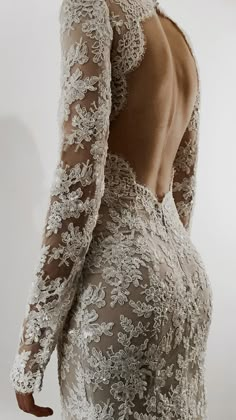 the back of a woman's wedding dress with long sleeves and lace on it