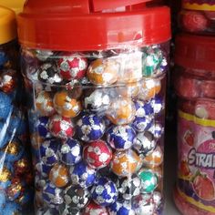 there are many colorful candies in the plastic container on the shelf next to each other