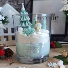 a glass filled with white frosting sitting on top of a table next to christmas decorations