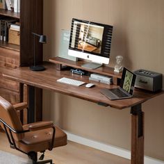 a computer desk with a laptop on top of it next to a chair and bookshelf