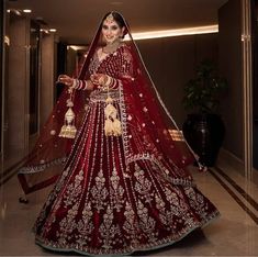 a woman in a red and gold bridal gown is posing for the camera with her hand on her hip