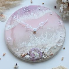 a pink clock with shells and seashells around it on a white table top