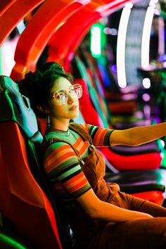 a woman sitting in a chair with her hand on the steering wheel while playing a video game