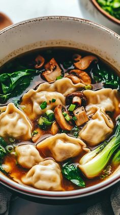 a white bowl filled with dumplings and broccoli on top of a table