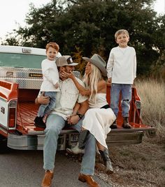 a family sitting on the back of a pickup truck