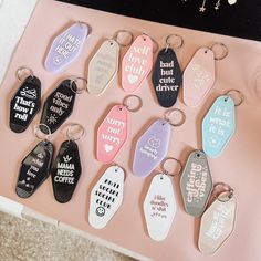 a bunch of key chains that are on a pink surface with some writing on them