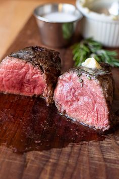 two pieces of meat sitting on top of a wooden cutting board