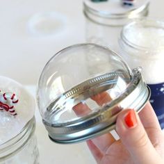 a hand is holding a jar with candy canes in it and other jars behind it