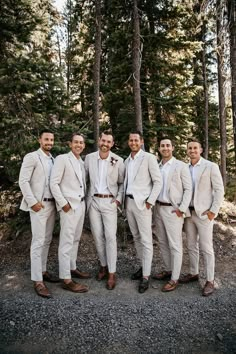 a group of men standing next to each other in front of some tall pine trees