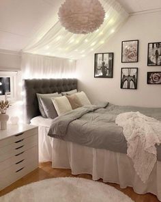 a bedroom with white walls and pictures on the wall above the bed, along with an area rug