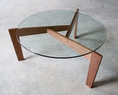 a glass table with wooden legs on concrete floor