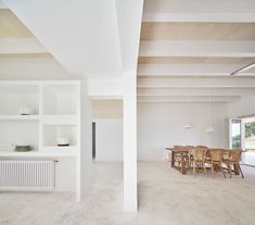 an empty room with white walls and wooden tables in the center is seen from across the room