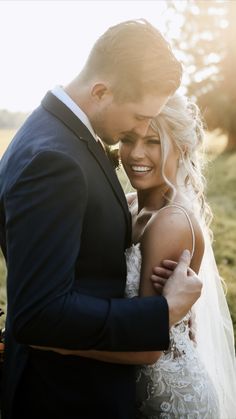 a bride and groom embracing each other in a field