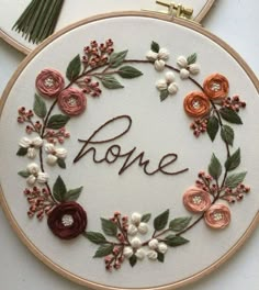 the embroidery hoop is decorated with flowers, leaves and words that spell home on it