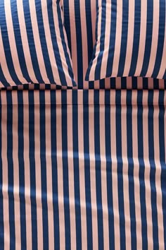 a blue and pink striped comforter with two pillows on it's back side