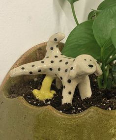 a ceramic dog figurine sitting on top of a potted plant in dirt