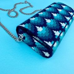 a blue and white purse sitting on top of a blue table next to a chain