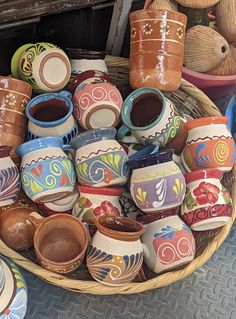 a basket filled with lots of different colored vases on top of a table next to other items