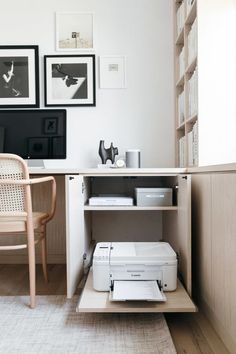 a white printer sitting on top of a wooden shelf in front of a computer desk