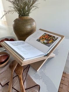 an open book sitting on top of a table next to a vase filled with flowers