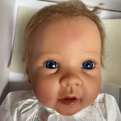 a baby doll with big blue eyes in a white shirt and bow tie looking at the camera