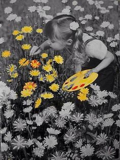 a girl picking flowers in a field with a yellow frisbee on the ground