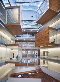 the inside of an office building with glass walls and wooden stairs leading up to it