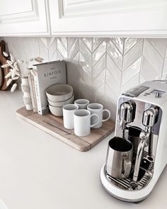 a coffee maker sitting on top of a kitchen counter next to cups and saucers