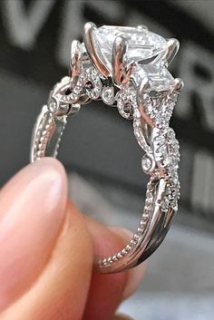 a close up of a person's hand holding an engagement ring