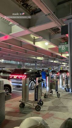 an empty parking garage with cars parked in the lot and luggage carts on the ground