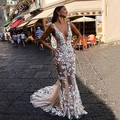 a woman in a long dress standing on the street