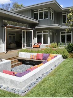 an outdoor living area with couches and fire pit in front of a large house