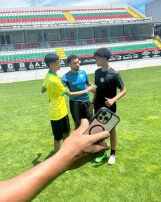 a person holding up a cell phone in front of two men on a soccer field