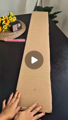 someone is making a cardboard table runner with flowers on the top and one hand reaching for it