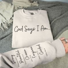 Introducing our Unisex God Says I AM sweatshirt, a cozy and stylish expression of faith. Crafted with comfort in mind, this sweatshirt features a unique design: God Says I am, printed on the front. The left sleeve displays a list of what God says we are and the bible verse associated with each quality and adjective, a powerful reminder of what we represent to God. Let this be your pick-me-up, motivational sweatshirt and a beautiful reminder to anyone who comes across it. Made from premium materi God Says I Am Shirt, Christian Clothing Ideas, Bible Verse Shirts For Women, God Says You Are, Unique T Shirt Designs Inspiration, God Says I Am, Cute Christian Sweatshirts, Christian Athletic Apparel, Christian Vinyl Shirts