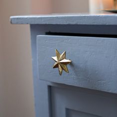 a close up of a blue dresser with a gold star decoration on the drawer knob