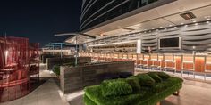 an outdoor bar and lounge area at night with green grass on the floor, lights in the background