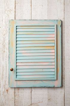 an old blue shuttered window on a white wooden wall with rusted knobs