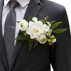 a man wearing a suit and tie with white flowers on his lapel flower bouquet