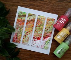 three different colored papers sitting on top of a table next to some bottles and paint