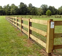 a wooden fence in the middle of a grassy field