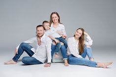 a family poses for a photo while sitting on the floor in front of a gray background